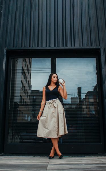 woman in beige sleeveless dress standing beside black wooden door