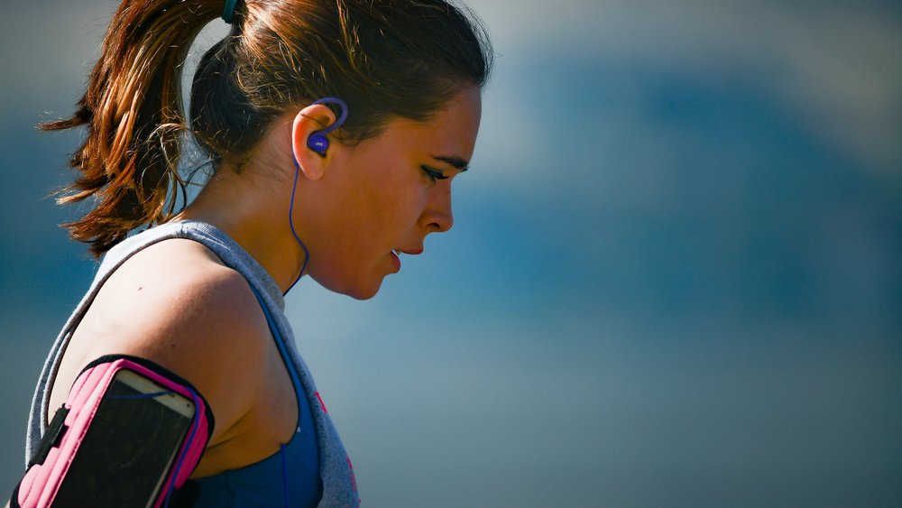 woman wearing smartphone armband and blue earphones