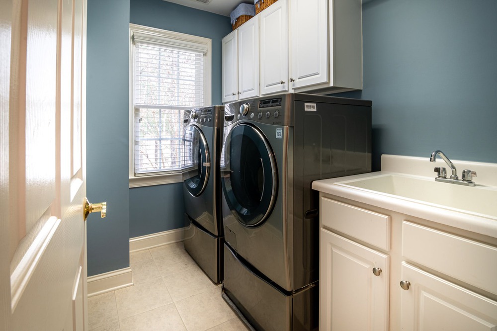 front load washing machine beside white window blinds