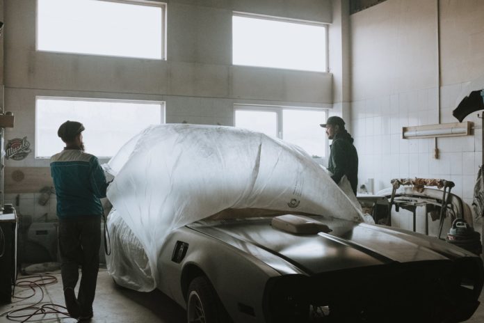 man in blue dress shirt and gray pants standing beside white car