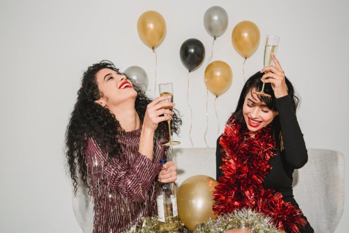 cheerful women with glasses of champagne and shiny balloons