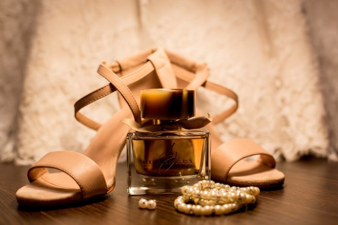 brown glass fragrance bottle beside white pearl bracelets
